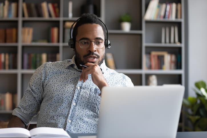 Focused Millennial Mixed Race Guy Consulting Clients Online.